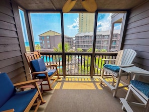 A balcony with wooden chairs and a view of buildings and a body of water.