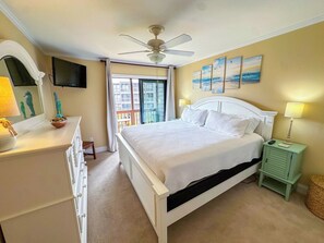A bedroom with a bed, a ceiling fan, a television, and artwork on the wall. - Tilghman Beach and Racquet Club 219 (North Myrtle Beach)