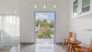 Een kamer met balkon, een eettafel met stoelen en uitzicht op een woonwijk.
