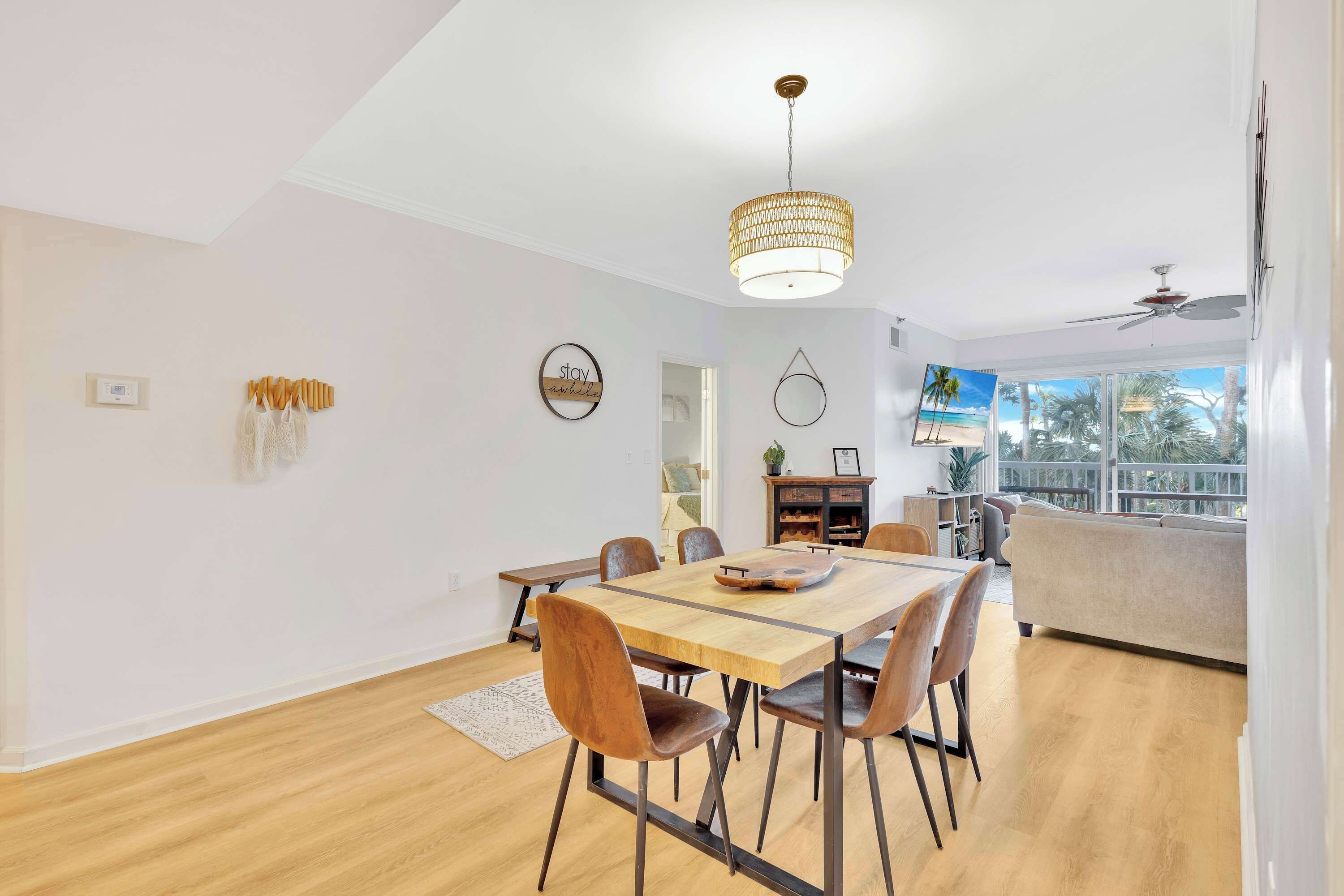 Un comedor moderno con una mesa y sillas de madera, una lámpara colgante y vistas al exterior.