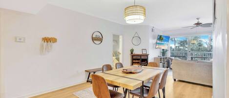 Un comedor moderno con una mesa y sillas de madera, una lámpara colgante y vistas al exterior.