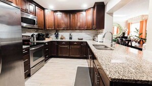 Una cocina moderna con armarios de madera oscura, electrodomésticos de acero inoxidable y encimera de granito.