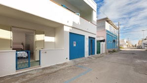A street view with a row of buildings, including a white building with a blue door and a blue building with a green door. - 3679 Mono Le Vele (Salve)