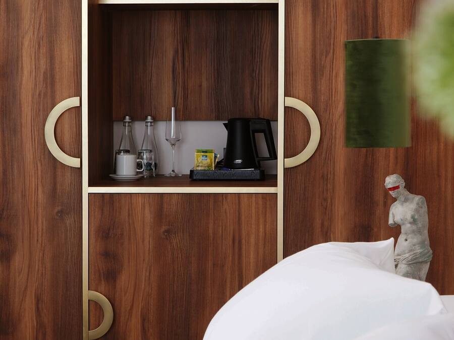 Un dormitorio con un armario de madera, una cama y una pequeña estatua.