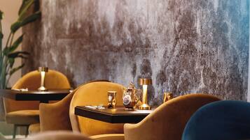 A dining area with a table set for two, featuring a gold teapot and cups.