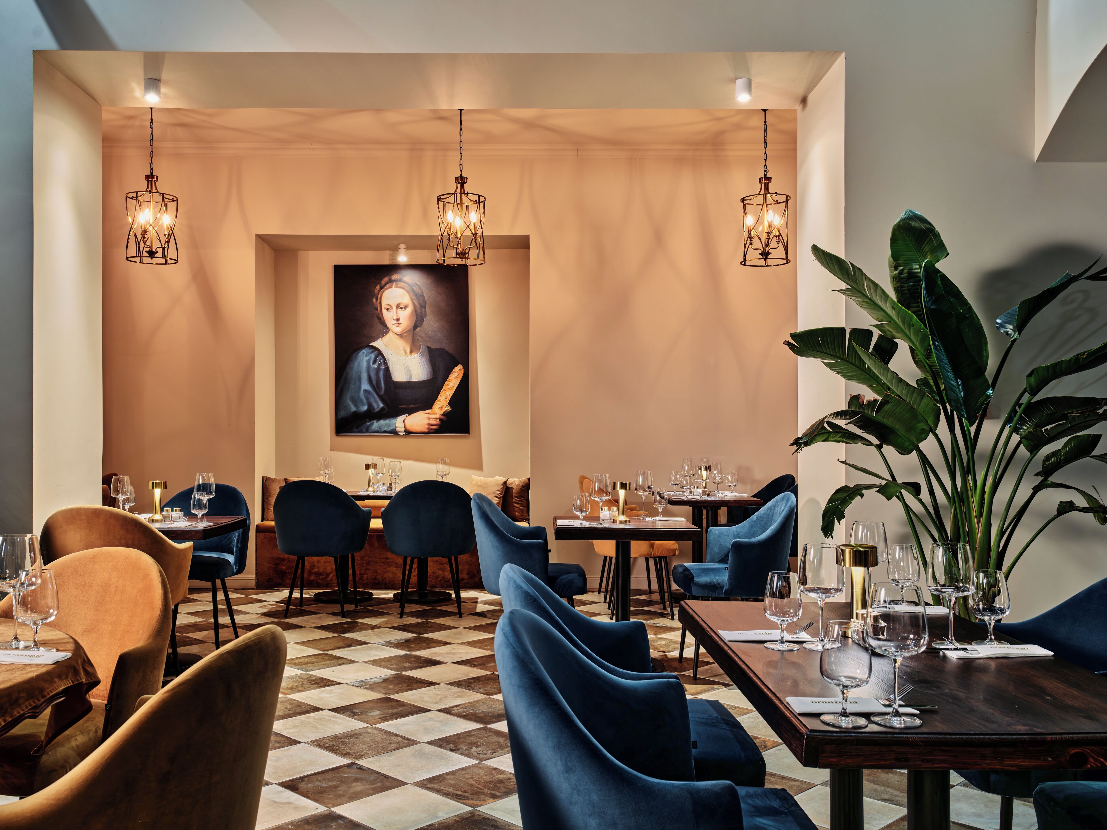 A restaurant with checkered flooring, blue and brown upholstered chairs, and a large painting on the wall.
