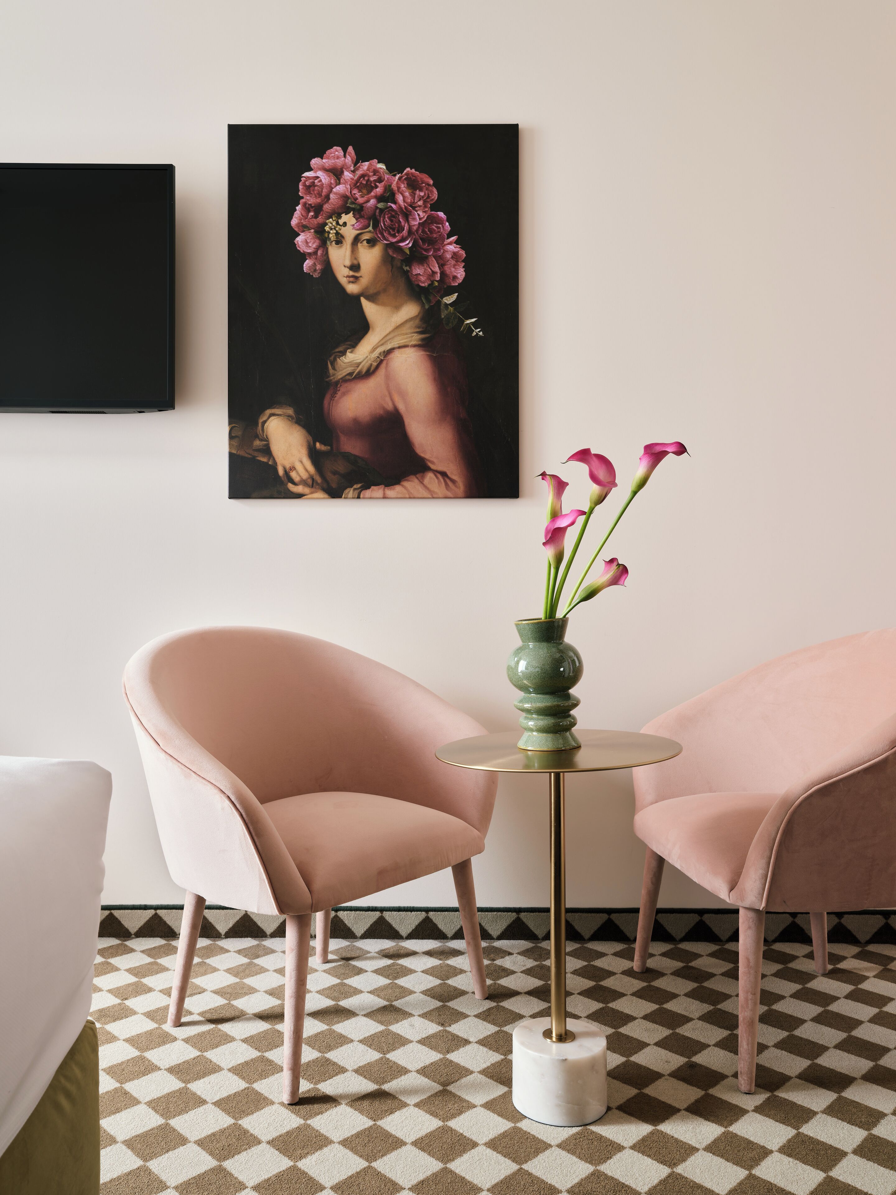 A room with two pink chairs, a round table with a green vase, and a checkered floor.