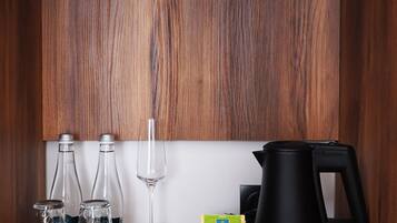 A wooden cabinet with a coffee maker, a glass, and a white cup on a wooden surface.