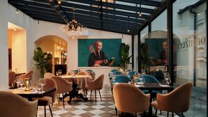 Restaurante moderno com piso xadrez, cadeiras contemporâneas e um lustre central.