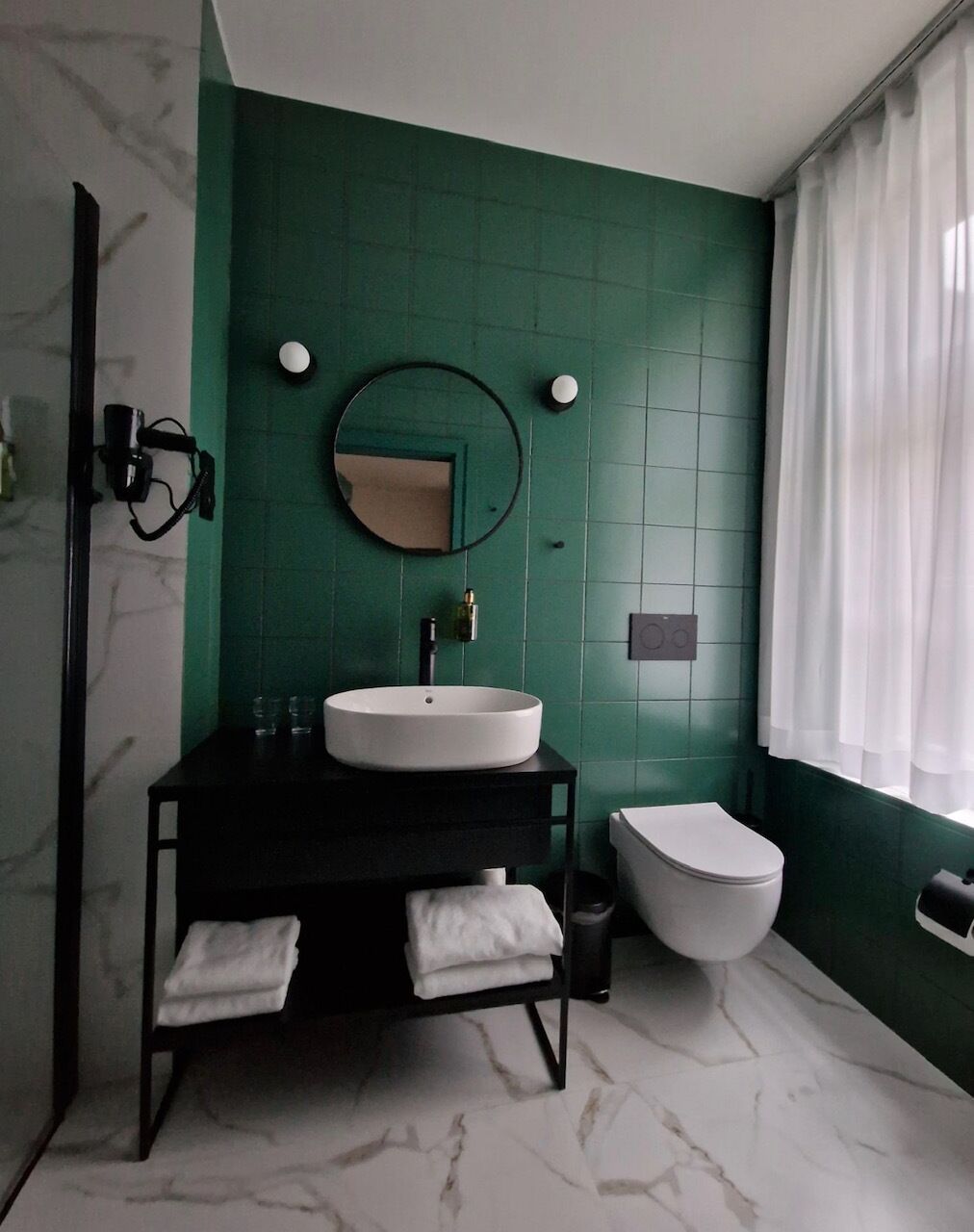 A bathroom with a black vanity, white sink, and toilet.