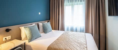 Una habitación de hotel con una cama, un escritorio y un televisor.