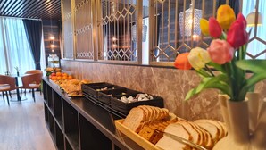 A buffet setup with various food items and a vase of tulips. - Hotel Fogo Amsterdam (Amsterdam)