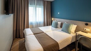 Una habitación de hotel con dos camas, un escritorio y un televisor.
