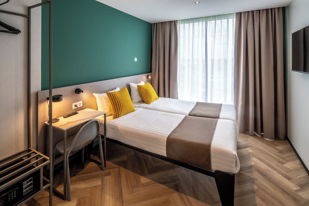 A hotel room with two beds, a desk, and a chair.