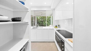 Een moderne keuken met witte kasten, een zwart aanrechtblad en een raam met uitzicht op groen.