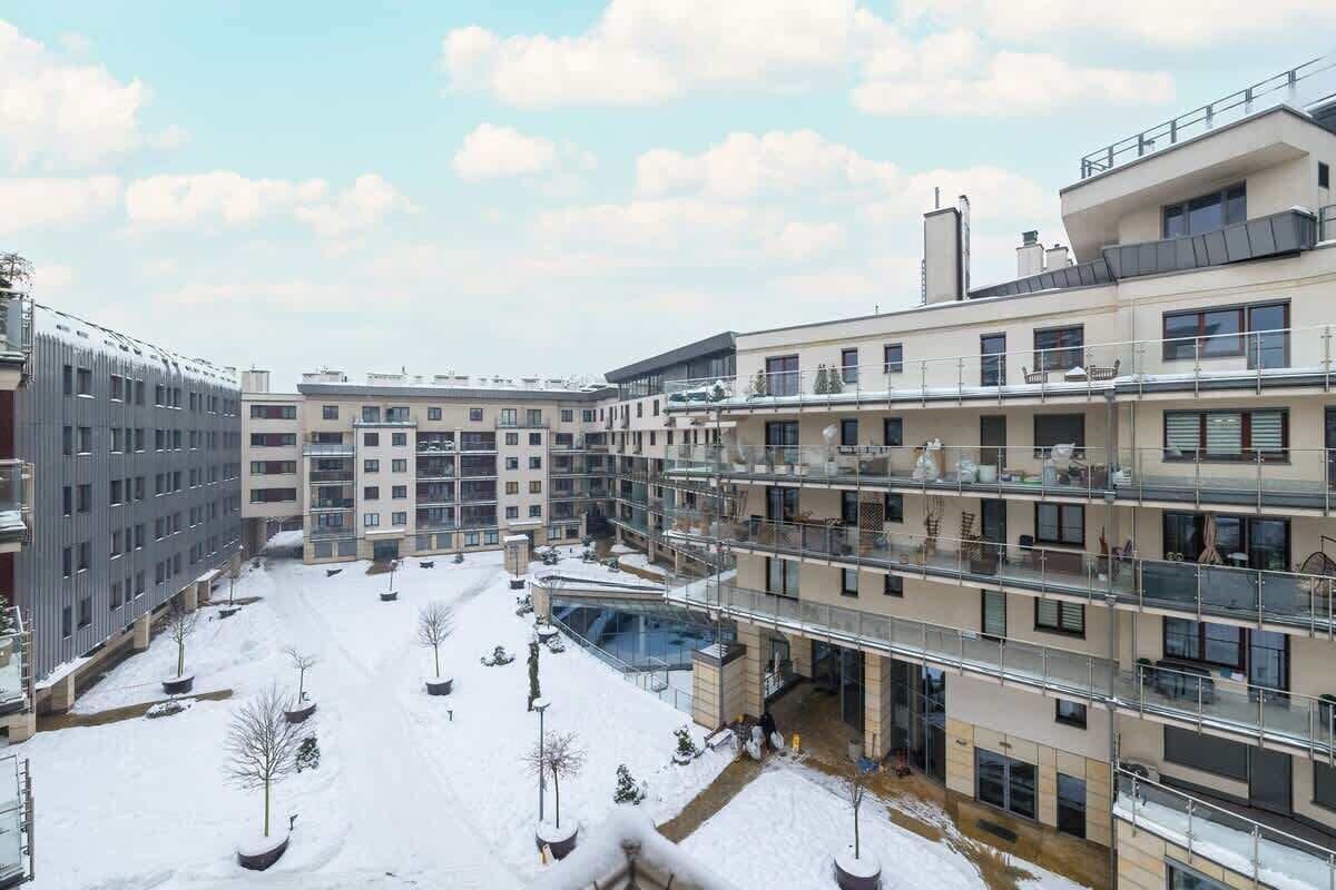 A multi-story residential building with balconies, a covered outdoor area, and a snow-covered courtyard.