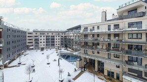A multi-story residential building with balconies, a covered outdoor area, and a snow-covered courtyard. - Spacious Apartment | Balcony, Parking, Pool (Kraków)