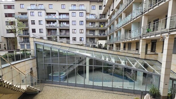 A multi-level atrium with glass railings, a central staircase, and a gravel courtyard. - Spacious Apartment | Balcony, Parking, Pool (Kraków)