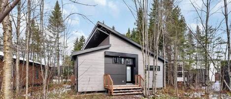 A small cabin with a sloped roof, a wooden deck, and a door with a window.