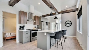 Une cuisine moderne avec un îlot central, des tabourets de bar et une horloge au mur.