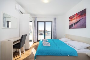 Hotellihuone, jossa on sänky, työpöytä, tuoli, ikkuna verhoilla ja seinällä taulu.