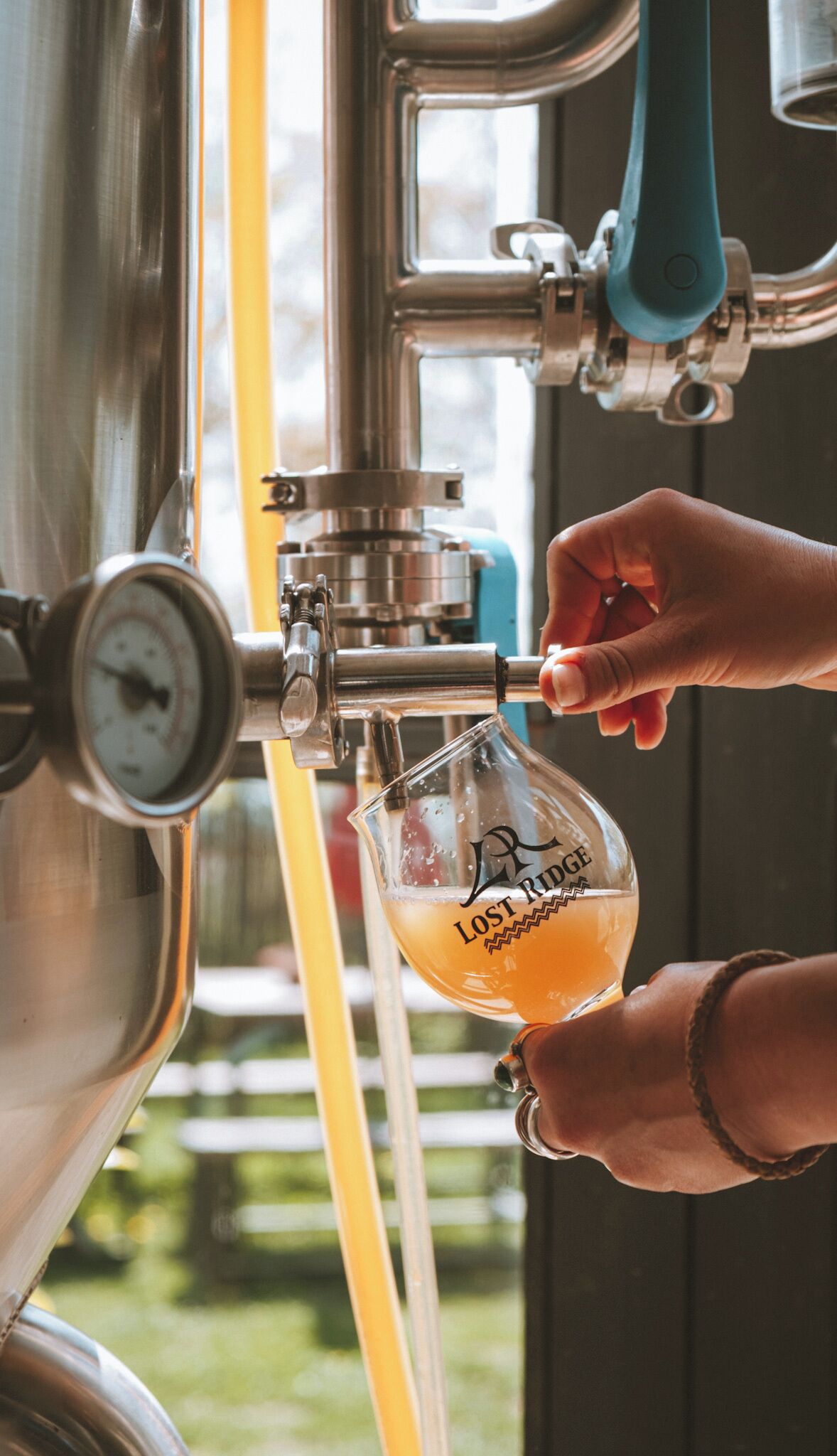 Una mano sirviendo cerveza de un grifo en un vaso con la etiqueta 'Lost Ridge'.