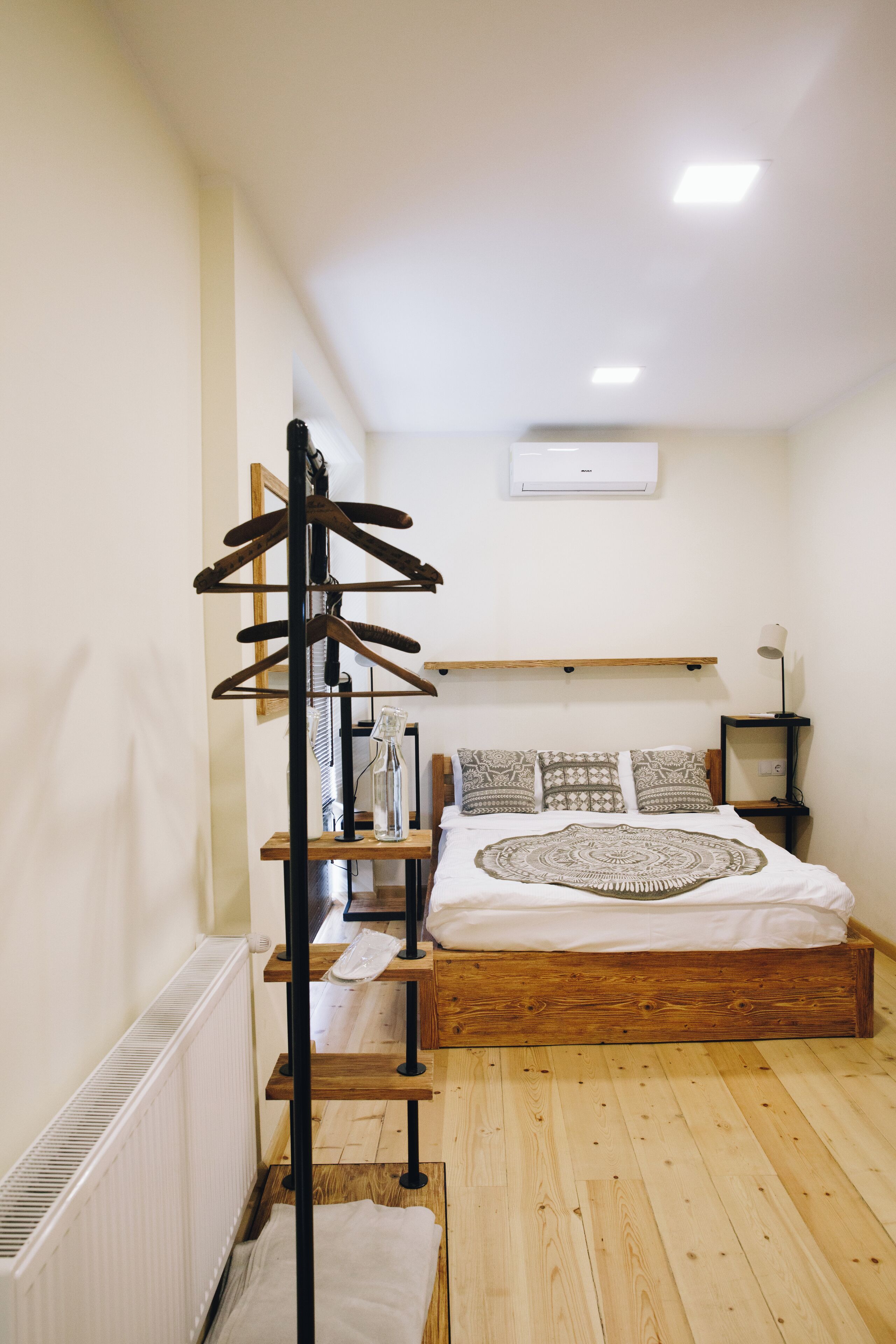 Et soveværelse med en træseng, et træknagepanel, et natbord med lampe og en radiator.