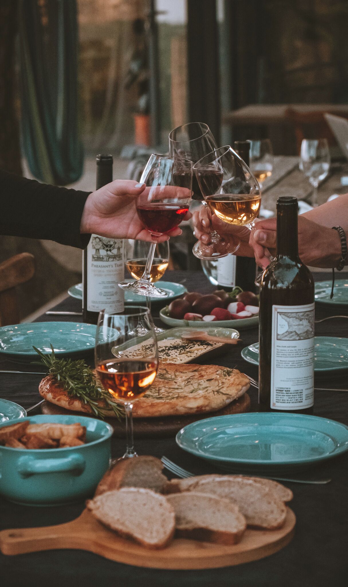A dining table with wine glasses, a bottle, and food items.