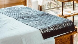 A bedroom with a bed, a hanging robe, and a view of trees through the window. - Lost Ridge Inn & Brewery & Ranch (Sighnaghi)