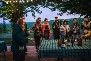 A group of people gathered around a table with bottles and glasses, likely for a social event. - Lost Ridge Inn & Brewery & Ranch (Sighnaghi)