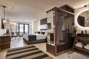 Une chambre d’hôtel moderne équipée d’un grand lit, d’un bureau, d’une chaise, d’une télévision et d’une salle de bain avec un miroir et un lavabo.