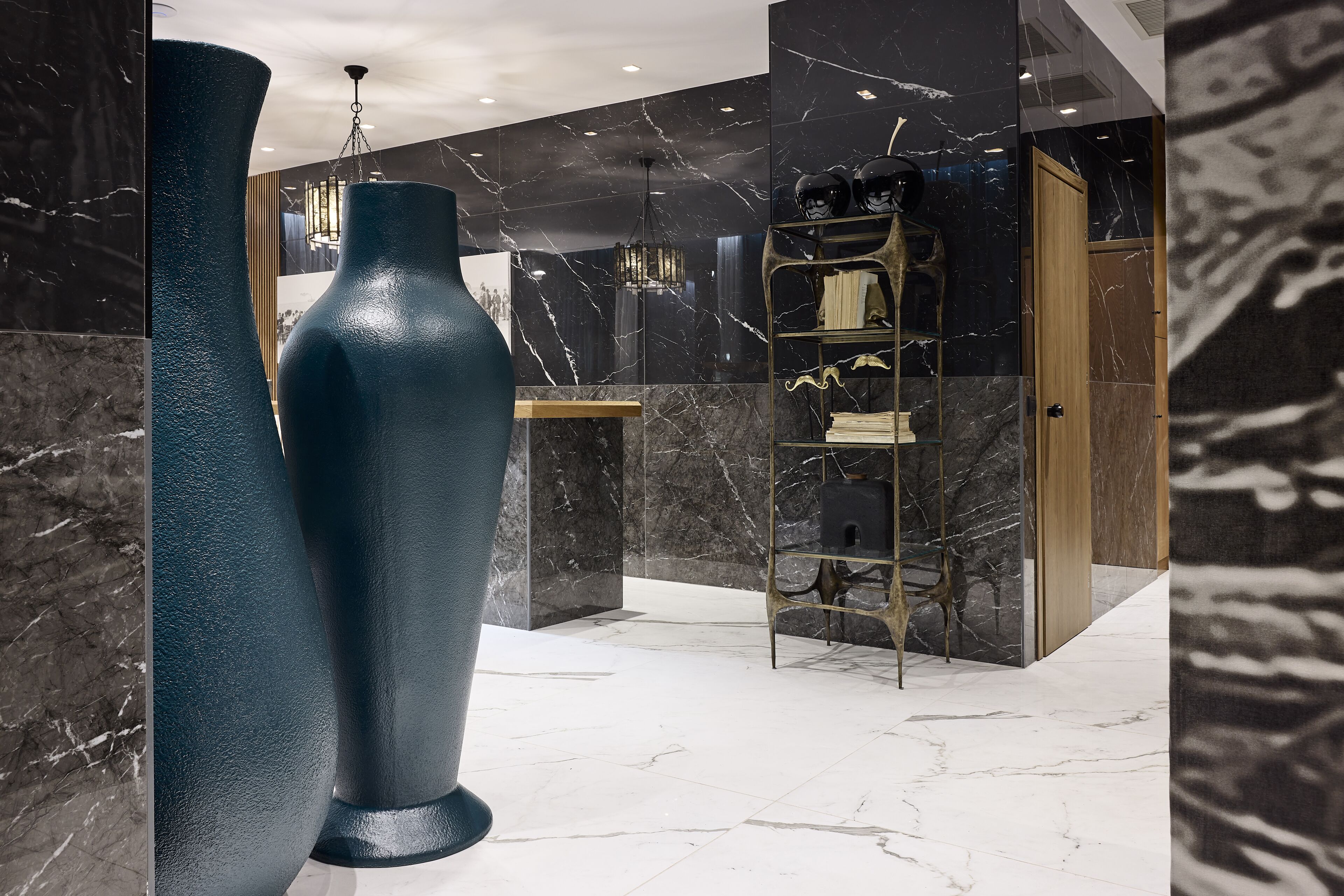 A modern lobby with marble walls, a large blue vase, and a metal ladder.