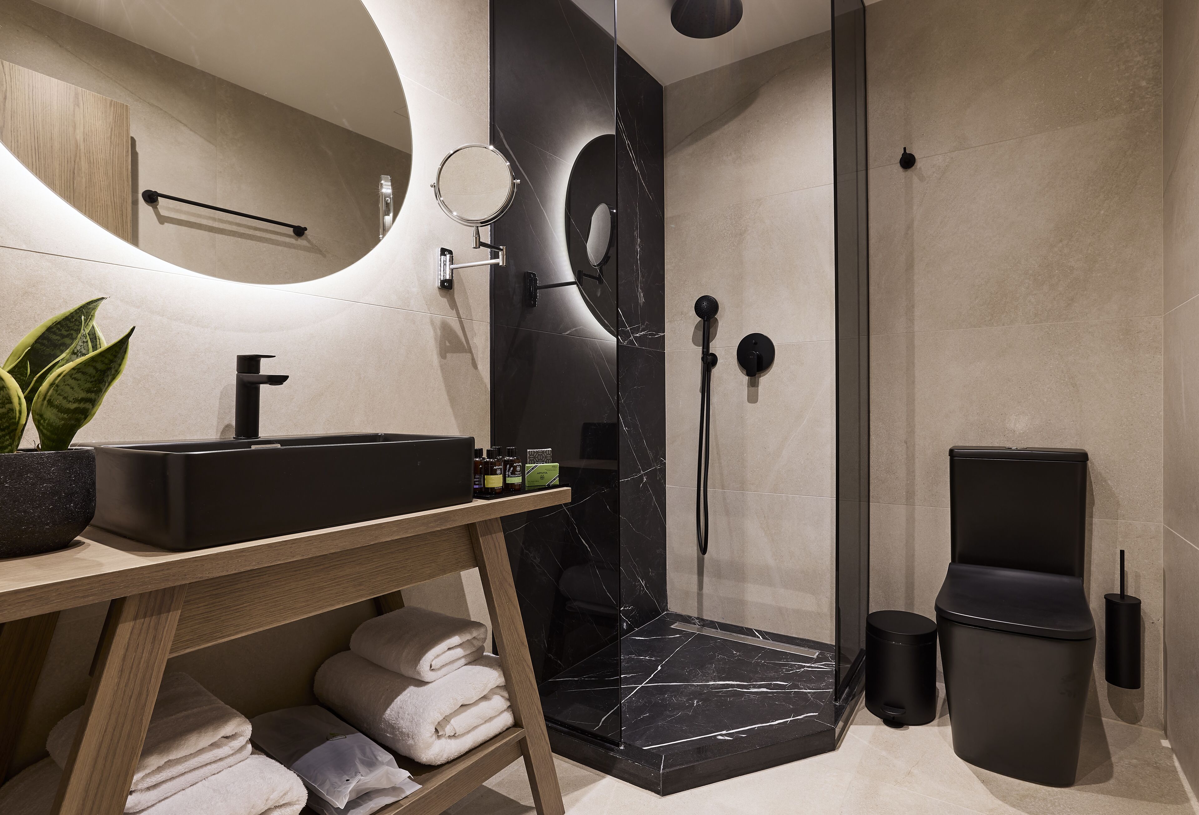 Ein modernes Badezimmer mit einer schwarzen Marmordusche, einem hölzernen Waschtisch und einem Spiegel.
