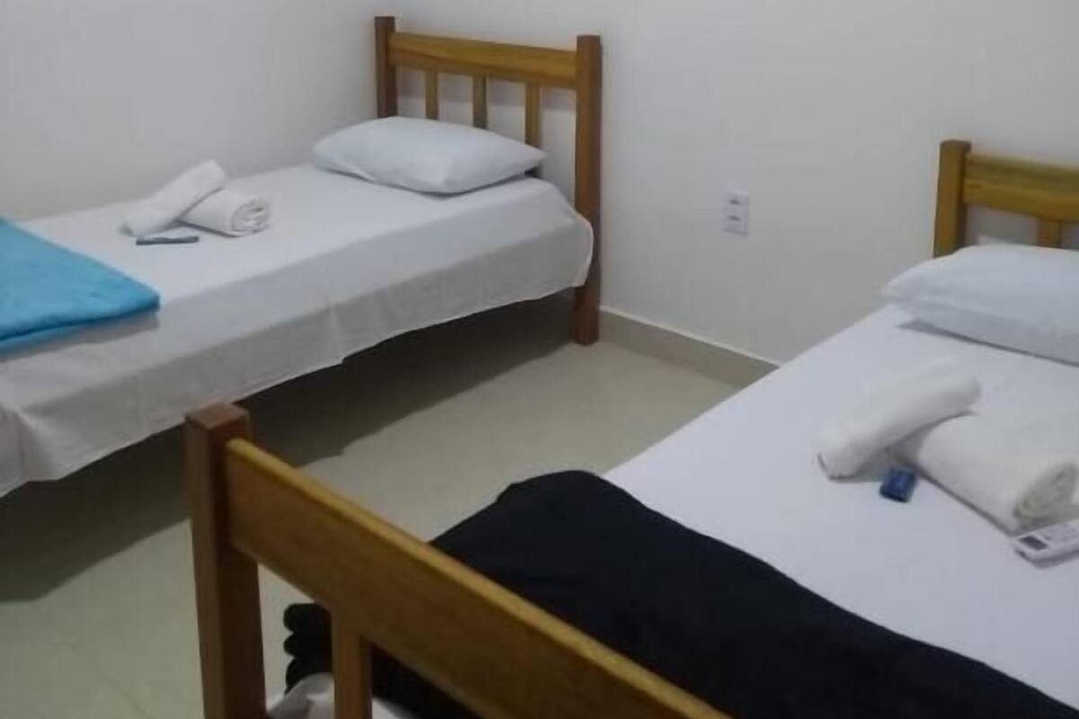 Ein Zimmer mit zwei Einzelbetten, jeweils mit Holzrahmen und weißer Bettwäsche.