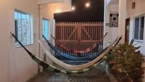 A modern interior with a hammock, a wooden bench, and a staircase leading to a balcony.