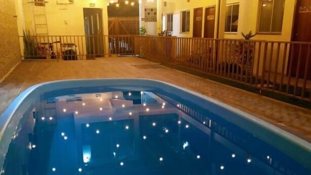 An indoor swimming pool with a tiled deck and a wooden fence surrounding it.