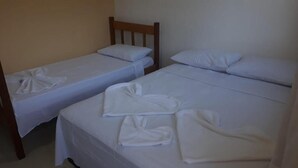 Two single beds with white linens and pillows, a wooden headboard, and a plain wall.