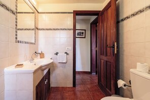 Ein Badezimmer mit Waschbecken, Spiegel, Toilette und einer TĂŒr zu einem weiteren Raum.