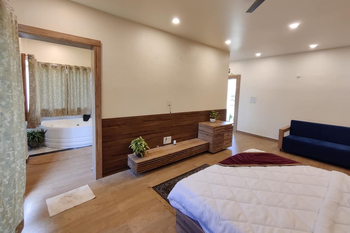Un dormitorio moderno con una cama grande, un banco de madera, una mesita con una planta y un ventilador de techo.
