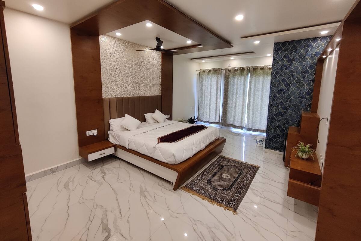 Un dormitorio moderno con una cama grande, un ventilador de techo y vistas al exterior a través de amplios ventanales.