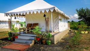 Una carpa blanca con un balcón y escalones de acceso, rodeada de varias macetas con plantas.