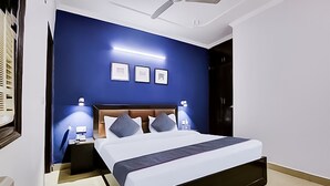 A modern bedroom with a large bed, dark blue walls, and a ceiling fan. - Roomshala 141 Agniv Residency (New Delhi)