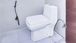A small, white bathroom with a toilet, a wall-mounted bidet, and a window above the toilet. - Roomshala 141 Agniv Residency (New Delhi)