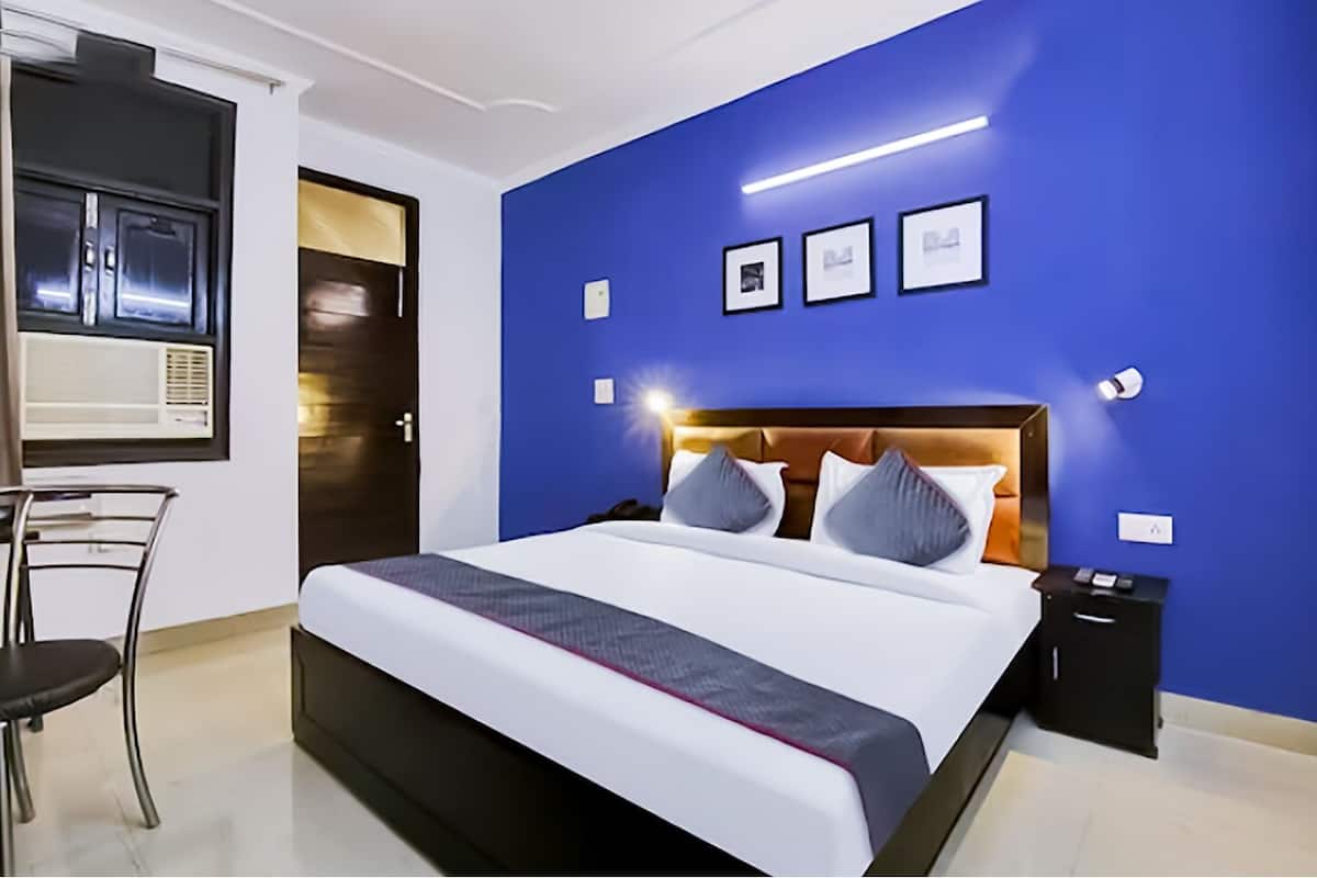 A modern hotel room with a large bed, a desk, and a chair.