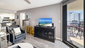 A modern living room with a flat-screen TV, a leather sofa, a dining area, and a balcony with outdoor furniture. - Phoenix VII 713 by Liquid Life (Orange Beach)
