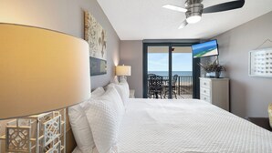A hotel room with a bed, a ceiling fan, a TV, and a balcony with a view of the sea. - Phoenix VII 713 by Liquid Life (Orange Beach)