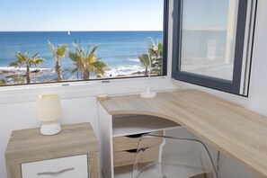 Une chambre avec un bureau, une lampe et une vue sur l’océan.