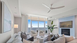 Ein modernes Wohnzimmer mit einer Couch, Sesseln, einem Couchtisch und einem Deckenventilator.