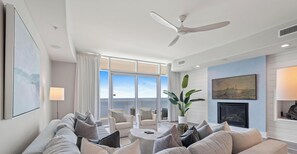 Una sala moderna con un sofá, sillones, una mesa de centro y un ventilador de techo.