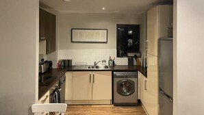 A compact kitchen with a dishwasher, sink, and a small refrigerator. - Charming 2-bed Apartment in Bow, London (London)